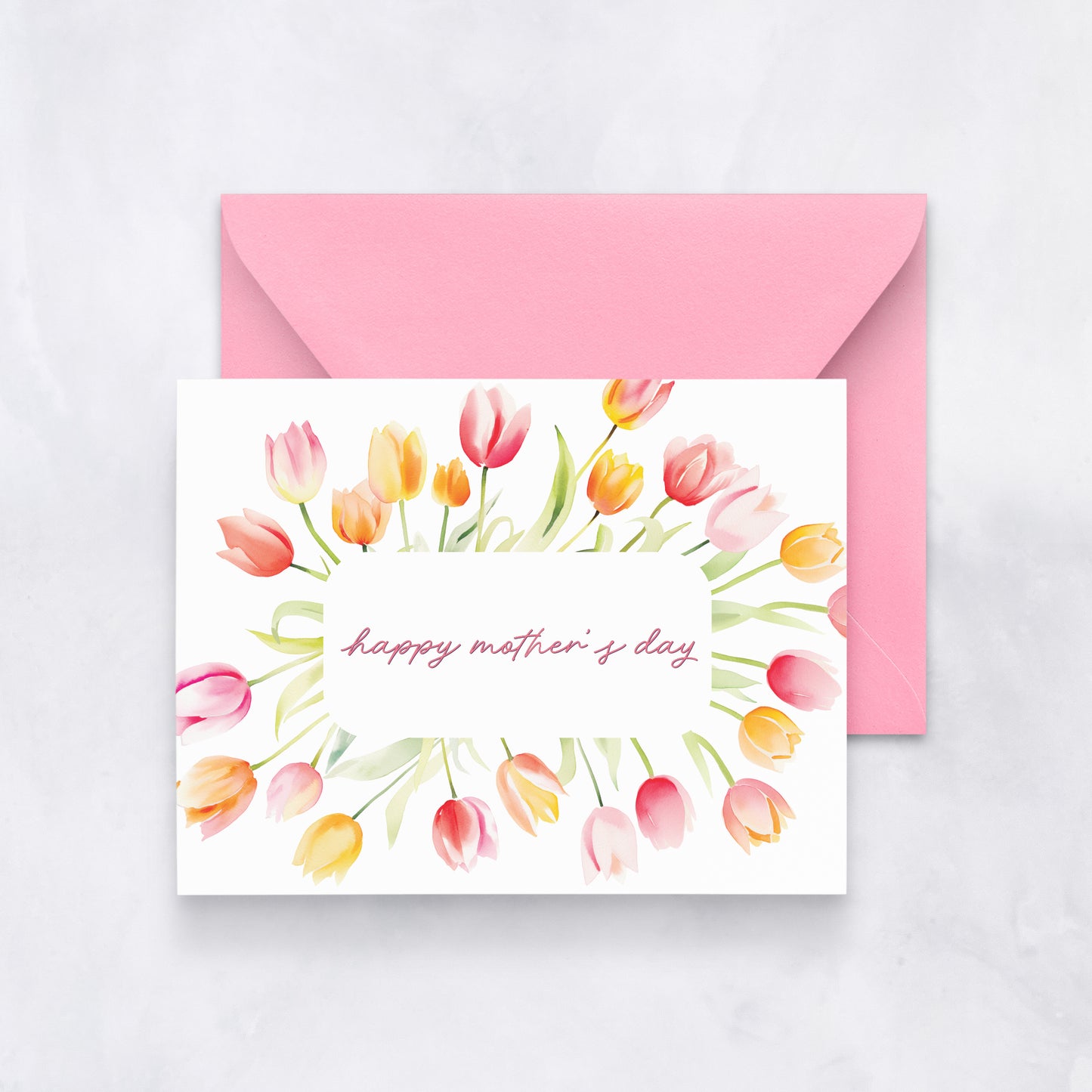 Greeting card with pink and yellow watercolor tulips surrounding the text “happy mother’s day,” paired with a pink envelope.