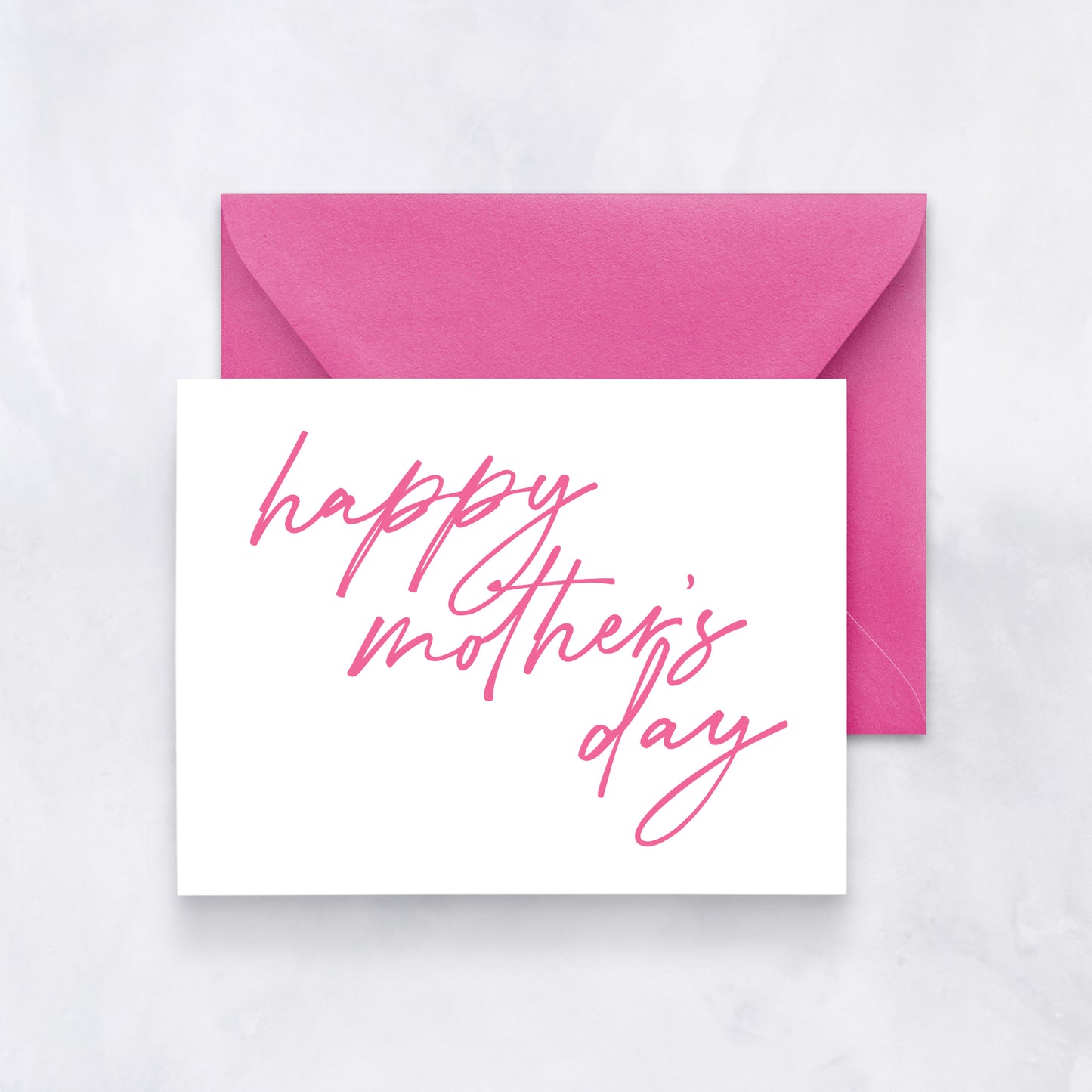 White greeting card with large pink script reading “happy mother’s day,” styled with a bright pink envelope.