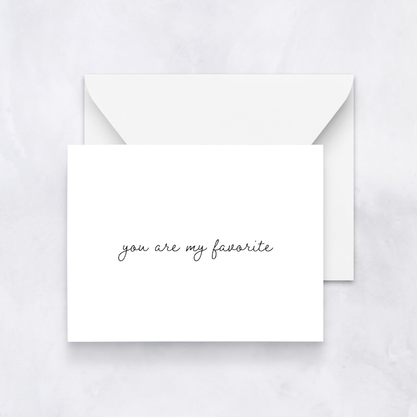 Minimal white greeting card with black handwritten text reading “you are my favorite,” styled with a white envelope on a soft neutral background.