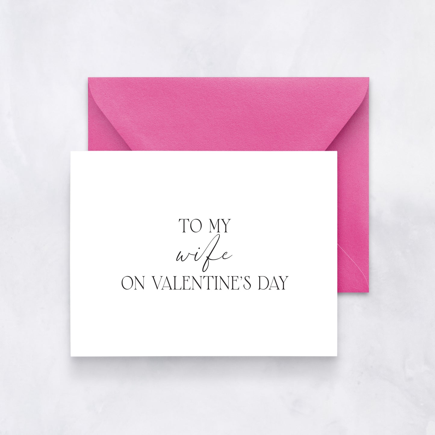 White card with elegant black script reading “To my wife on Valentine’s Day,” paired with a pink envelope.