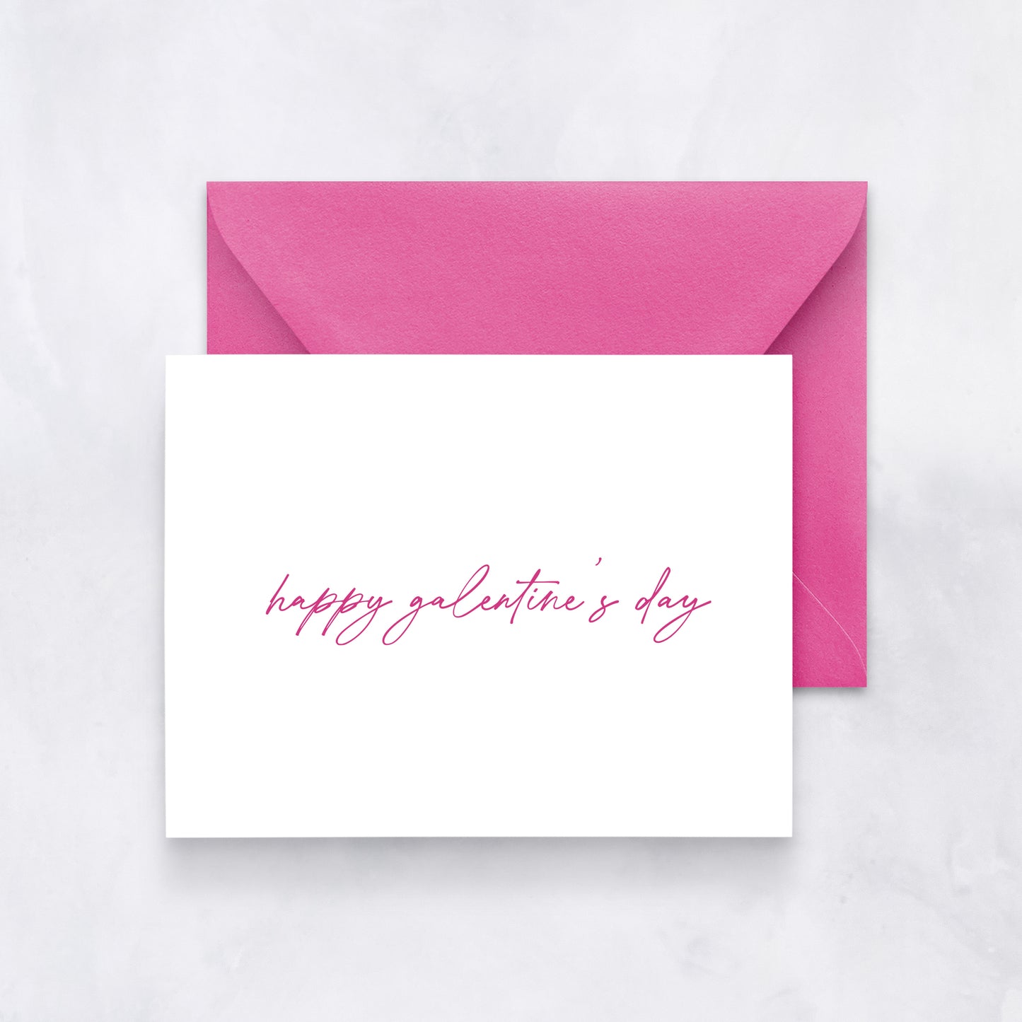White card with handwritten pink script reading “happy galentine’s day,” paired with a pink envelope.