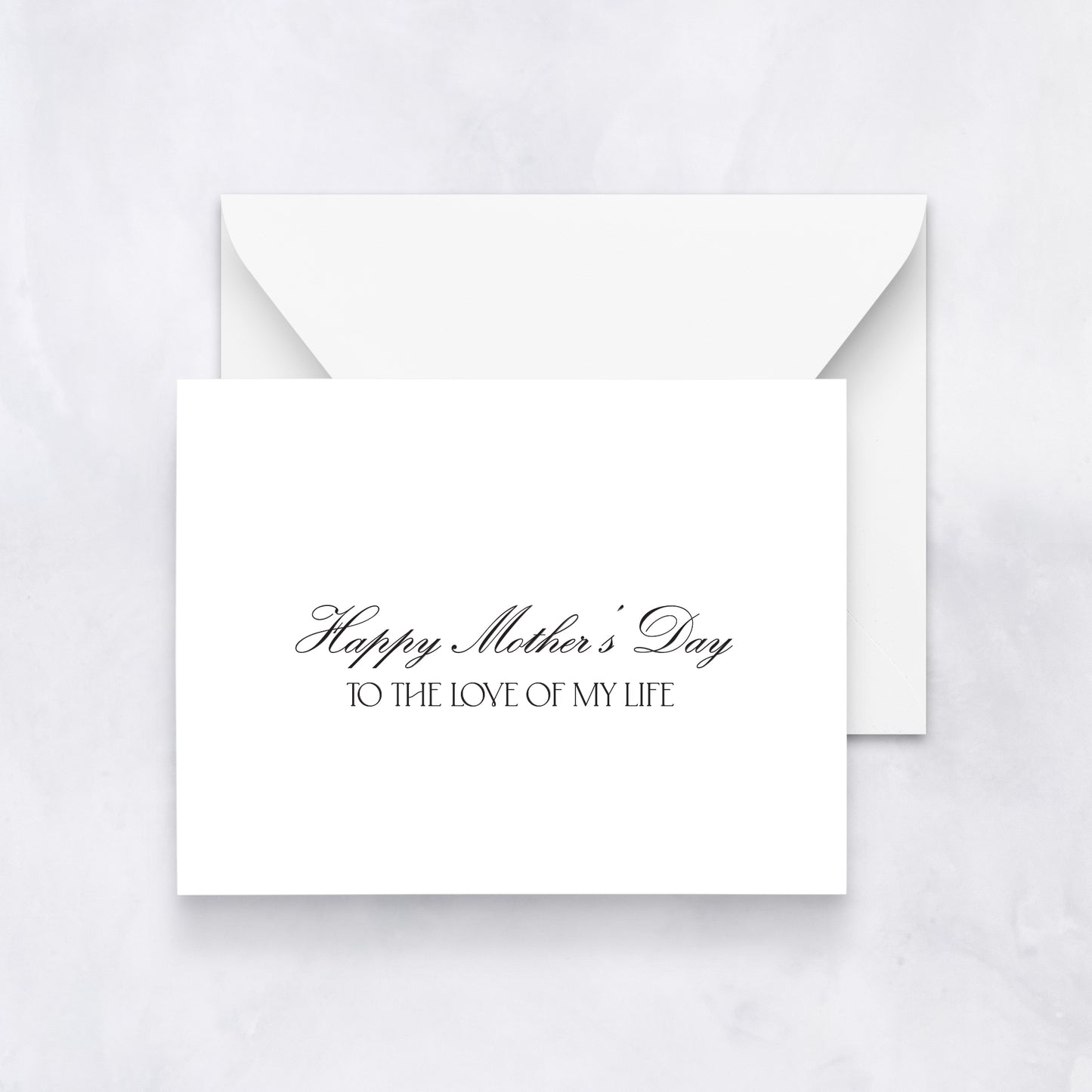 White greeting card with black script text reading “Happy Mother’s Day to the love of my life,” styled with a white envelope on a neutral background.