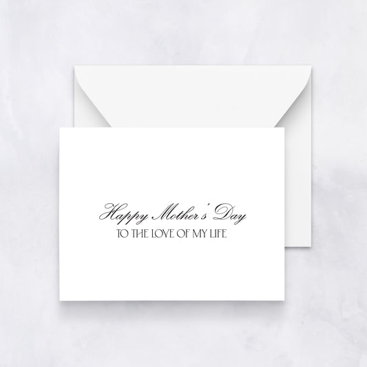 White greeting card with black script text reading “Happy Mother’s Day to the love of my life,” styled with a white envelope on a neutral background.