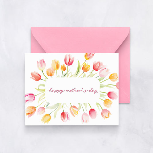 Greeting card with pink and yellow watercolor tulips surrounding the text “happy mother’s day,” paired with a pink envelope.