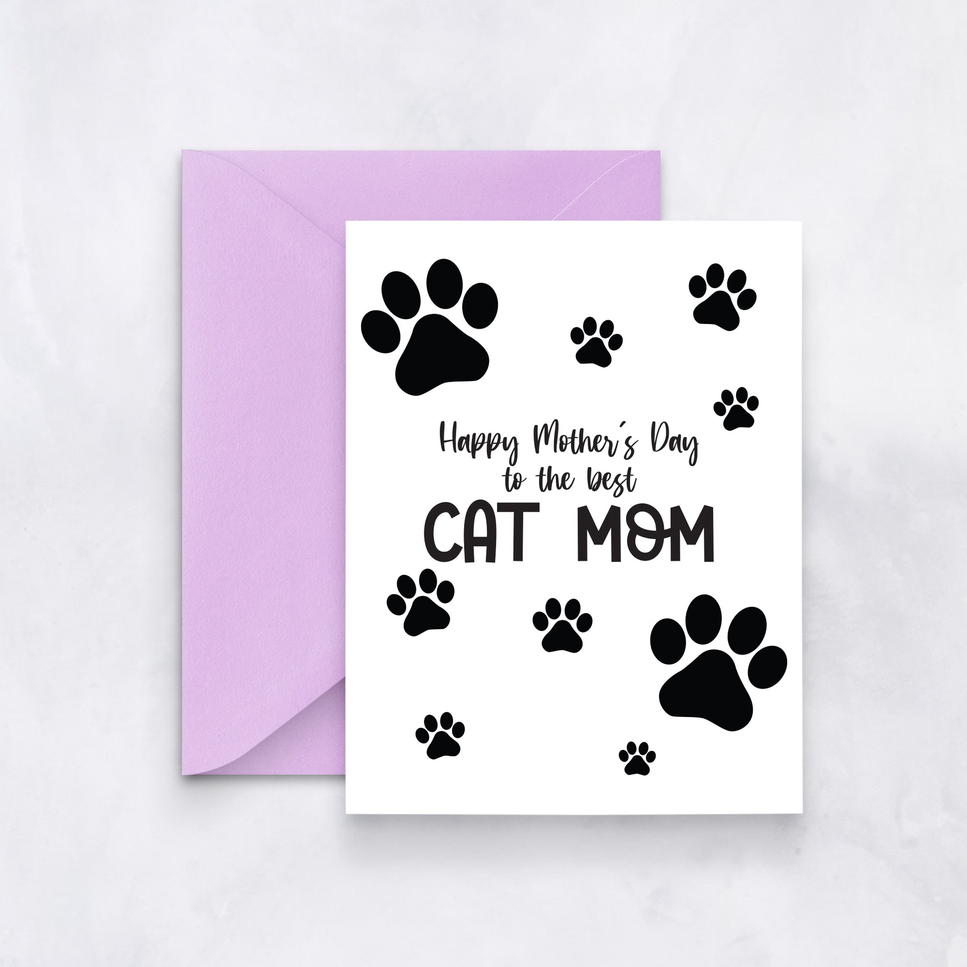 White greeting card with black paw prints and the message “Happy Mother’s Day to the best cat mom,” styled with a lavender envelope.