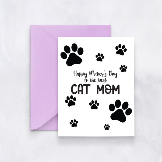White greeting card with black paw prints and the message “Happy Mother’s Day to the best cat mom,” styled with a lavender envelope.