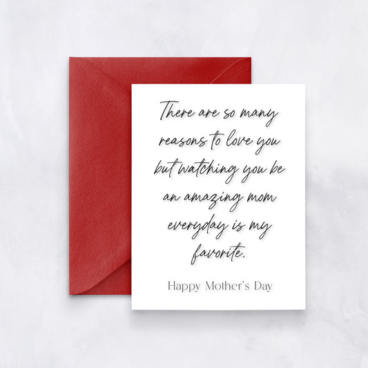 White greeting card with black cursive text reading “There are so many reasons to love you but watching you be an amazing mom everyday is my favorite. Happy Mother’s Day,” styled with a red envelope.