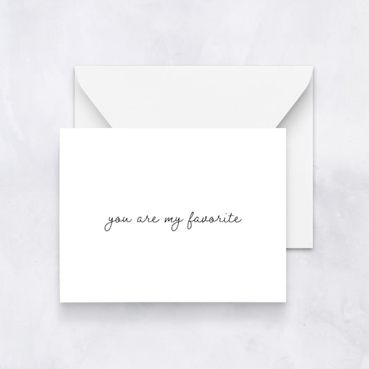 Minimal white greeting card with black handwritten text reading “you are my favorite,” styled with a white envelope on a soft neutral background.
