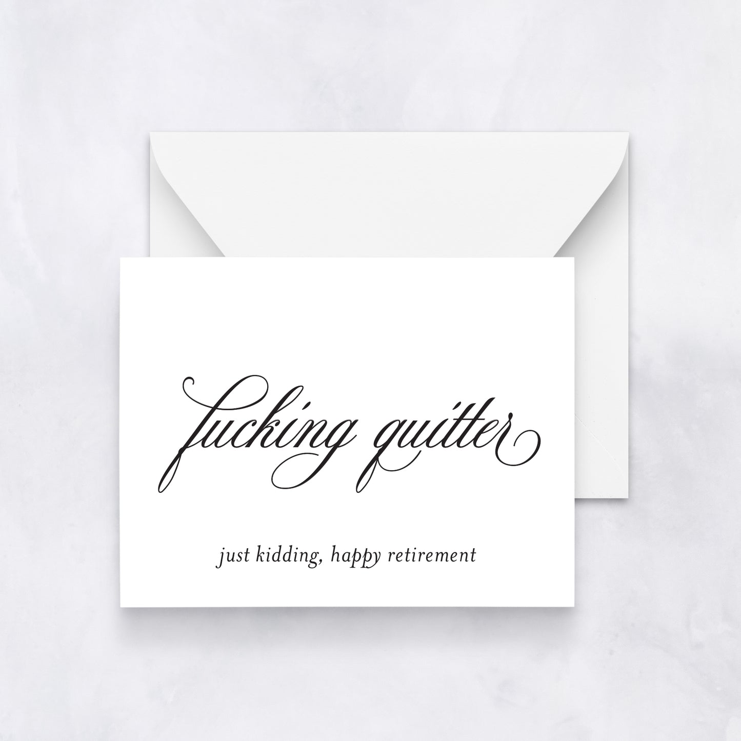 White card with elegant black script reading “fucking quitter” and small text below “just kidding, happy retirement,” styled with a white envelope.