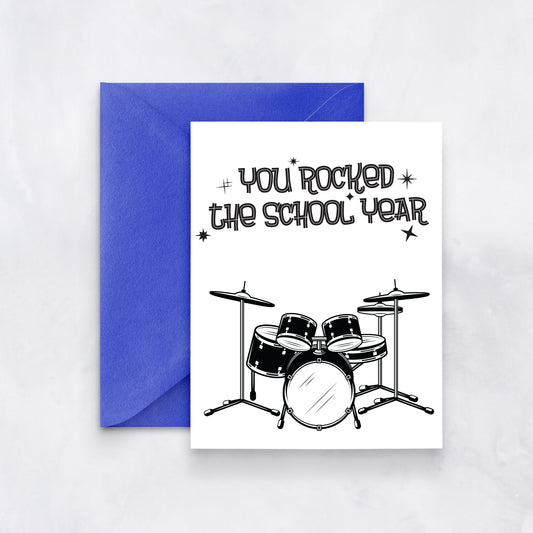 White card with black drum set illustration and text reading “You rocked the school year,” paired with a royal blue envelope.