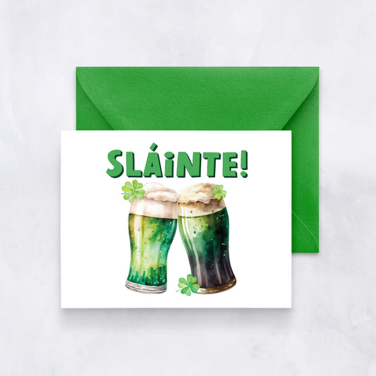 White card with watercolor illustration of two green beers clinking under bold green text “Sláinte!”, paired with a bright green envelope.
