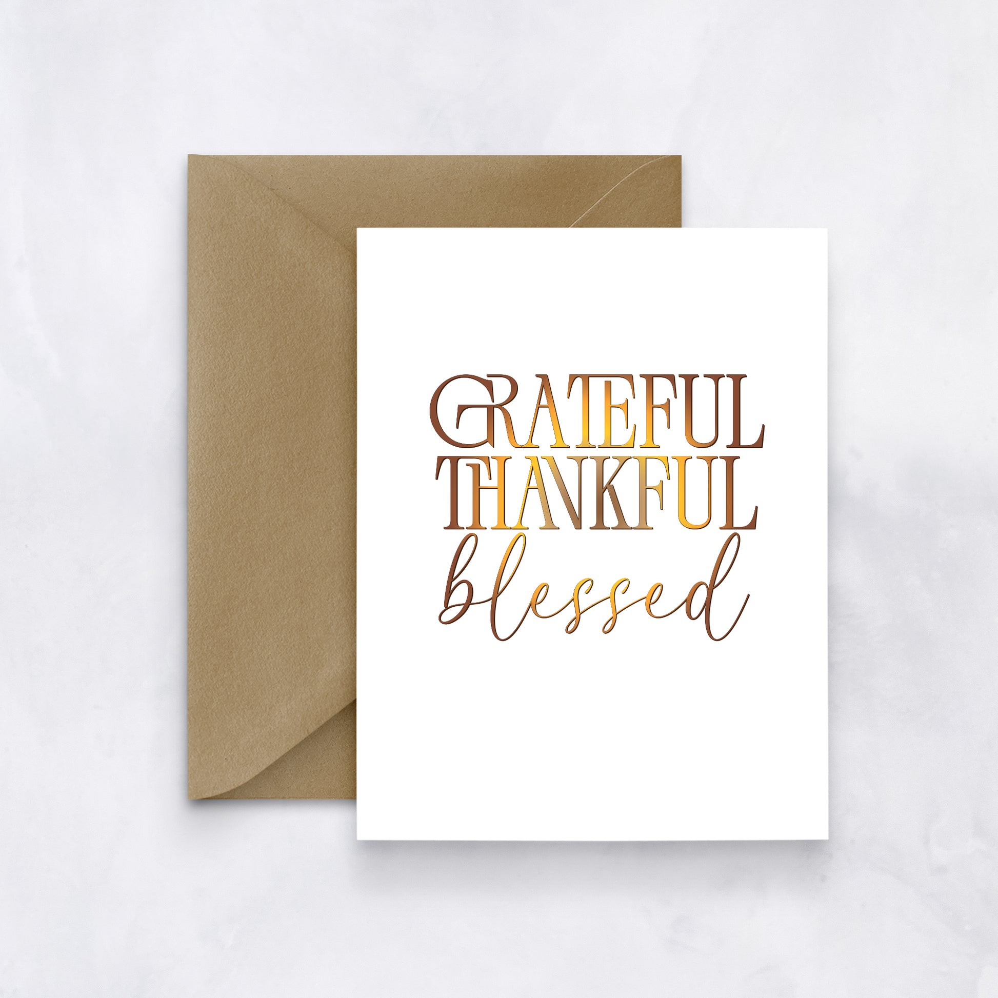 White card with layered text reading “Grateful Thankful Blessed” in warm autumn gradient tones, styled with a tan envelope.