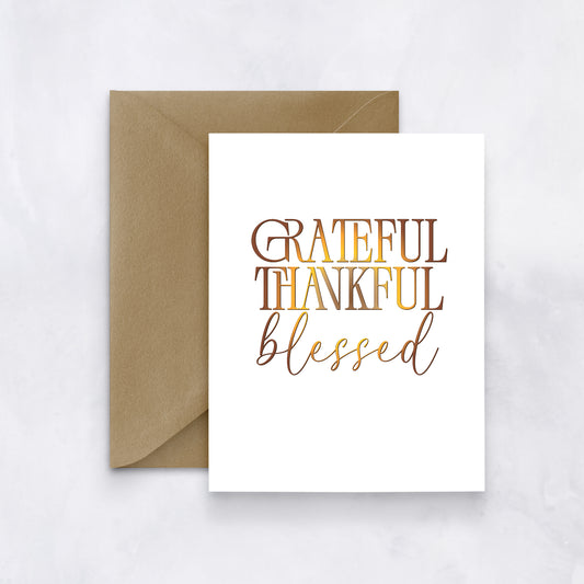 White card with layered text reading “Grateful Thankful Blessed” in warm autumn gradient tones, styled with a tan envelope.