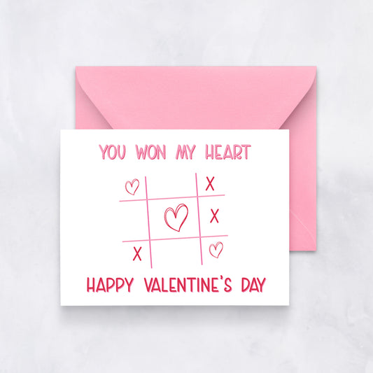 White card with pink tic-tac-toe grid and hearts, text “You won my heart – Happy Valentine’s Day,” paired with a pink envelope.