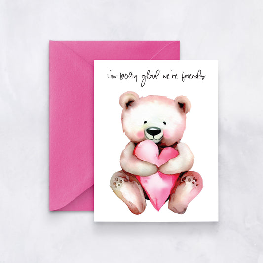 White card with watercolor teddy bear holding a pink heart, text reads “I’m beary glad we’re friends,” paired with a pink envelope.