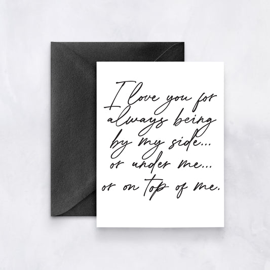 White card with black handwritten script reading “I love you for always being by my side… or under me… or on top of me,” styled with a black envelope.