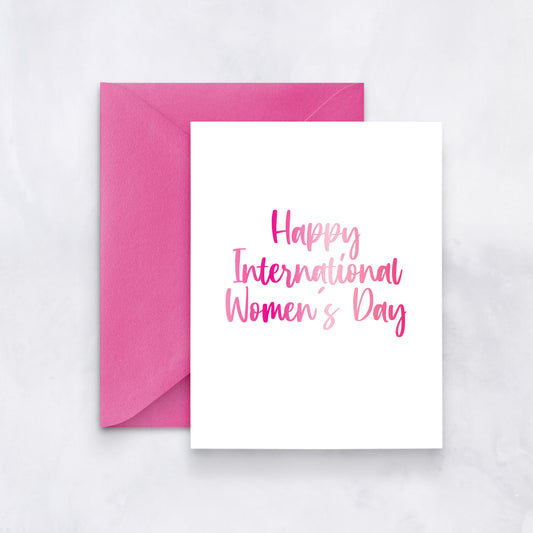 White card with pink gradient script reading “Happy International Women’s Day,” styled with a vibrant fuchsia envelope.