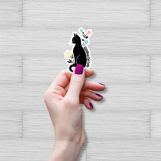 Hand holding a black cat with flowers sticker on a gray textured background