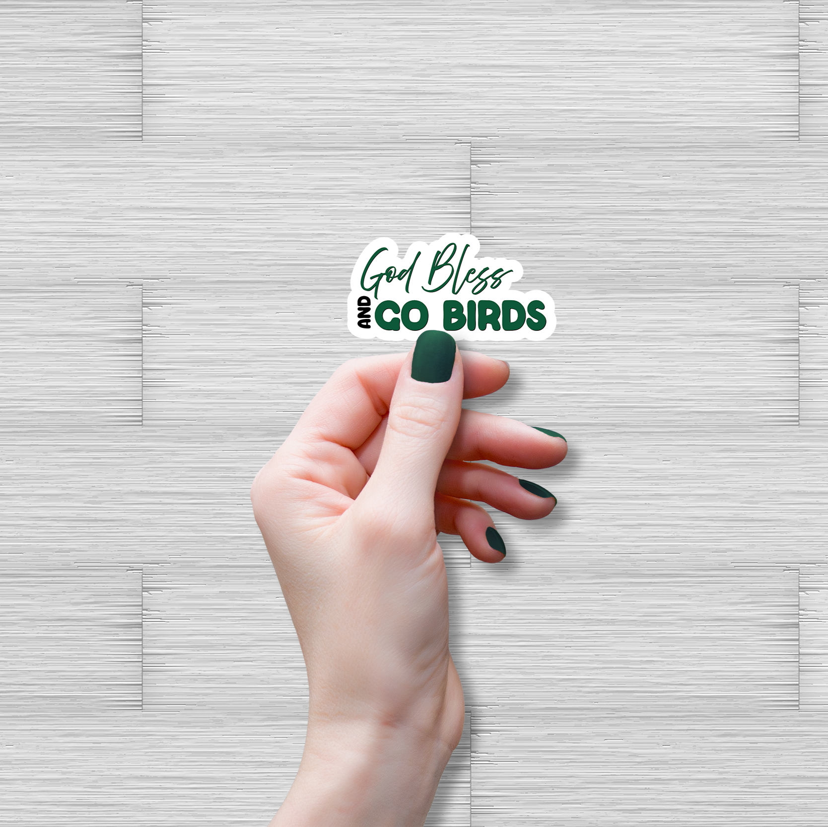 Hand holding a sticker with 'God Bless Birds' text on a textured gray background
